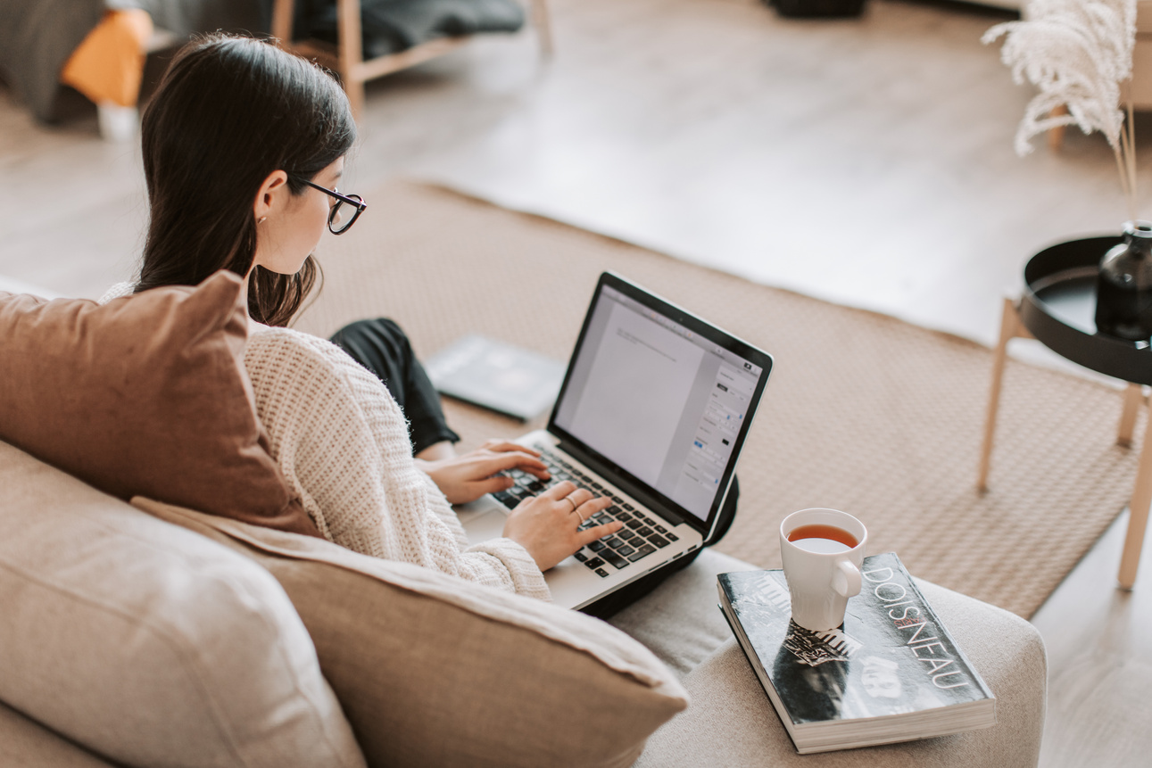 Young woman typing on laptop on sofa